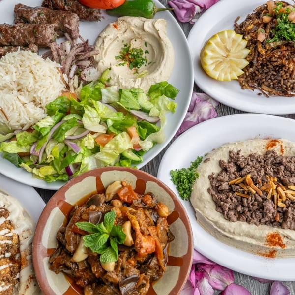 A spread of Lebanese dishes, including kebabs, rice, salad, hummus, and stewed vegetables.