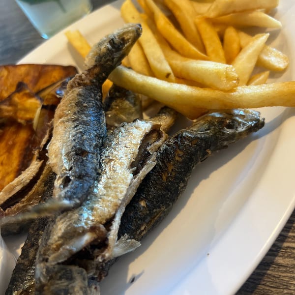 Fried sardines and french fries on a white plate at Omaya's Lebanese Cuisine.