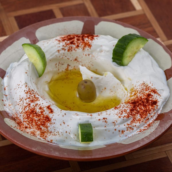 Omaya's Lebanese Cuisine labneh, garnished with olive oil, a green olive, paprika, and cucumber slices.